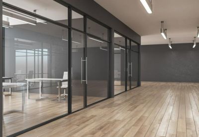 Modern hallway with glass partitions looking into private office suites and polished wood floors.
