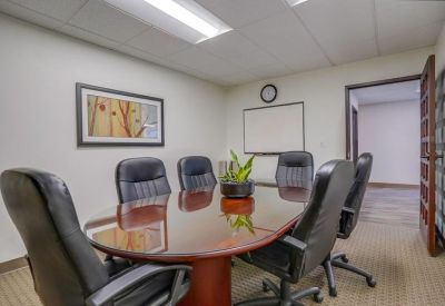 Professional boardroom featuring a polished wood table, leather chairs, and wall art.