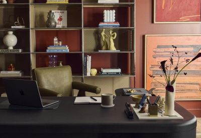 Executive office desk with an olive green leather chair set against red walls and custom shelving.