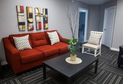 Bright lounge area featuring a bold red sofa, patterned pillows, and modern wall decor.