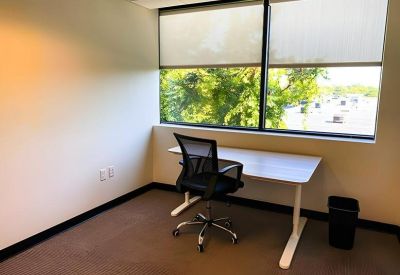 Private office featuring a height-adjustable desk and large window with views of lush greenery.