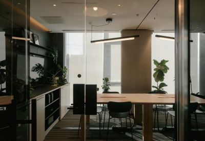 Glass-walled conference room with a light wood table and view of indoor plants.