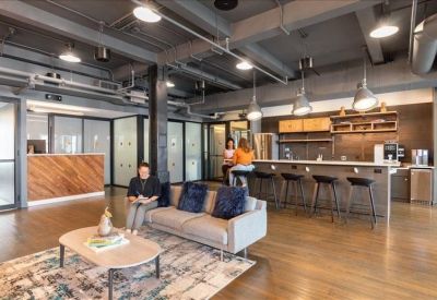Spacious lounge and kitchen area with industrial ceilings, a sofa, and bar seating.
