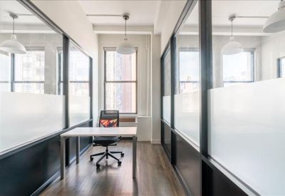 Bright glass-walled private office with a white desk and city views.