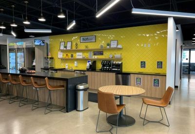 Communal kitchen area with a bright yellow backsplash, bar seating, and modern appliances.