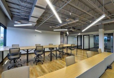 Modern conference room with a long table, ergonomic chairs, and industrial exposed ceiling.