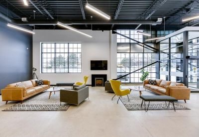 Bright lounge area with tan leather sofas, yellow armchairs, and a modern fireplace.