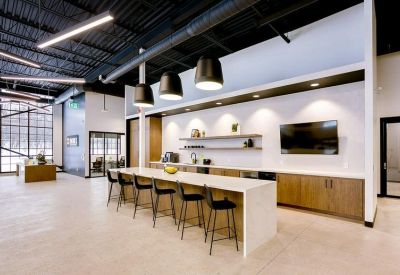 Contemporary breakroom and kitchen area with a long white island and bar seating.