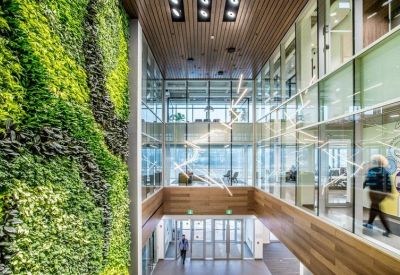 Modern multi-story atrium featuring a massive lush green living wall and glass railings.