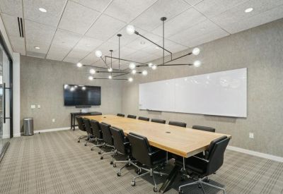 Large conference room featuring a long wooden table, black leather chairs, and a geometric chandelier.