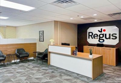 Reception area with a light wood front desk and black leather waiting chairs.