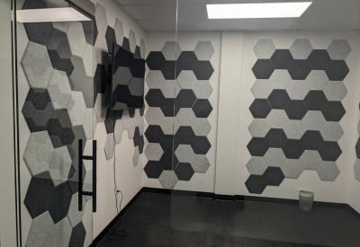 Small private office room featuring a grey and white hexagonal sound-absorbing wall pattern.