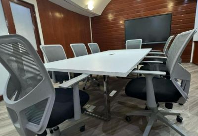 Professional boardroom with a white table, grey ergonomic chairs, and wood-paneled walls.