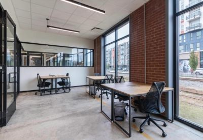 Bright office space with wooden desks and industrial brick walls.