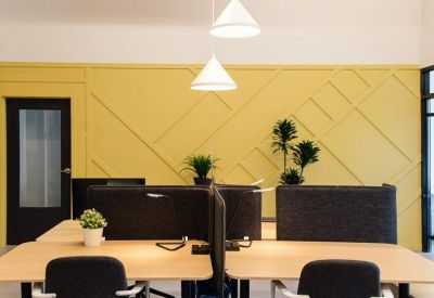 Modern workstations with black chairs and a yellow feature wall with geometric patterns.