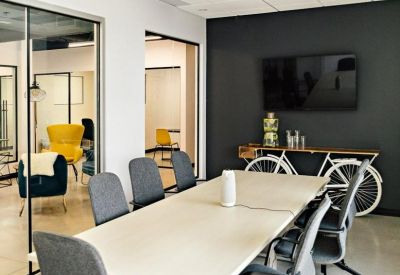 Modern meeting room with a long white table, grey ergonomic chairs, and a decorative bicycle console.