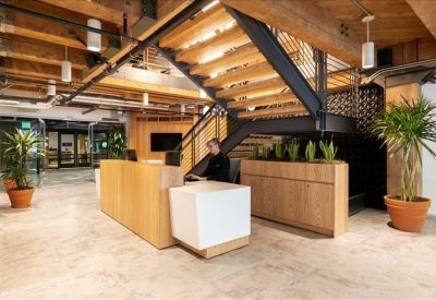 Reception area featuring a wooden desk, potted plants, and a grand industrial staircase.