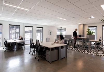Bright open-plan office with white desks, ergonomic chairs, and large windows.