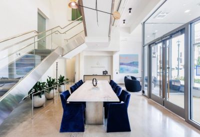 Sleek reception area with a wooden conference table, blue velvet chairs, and a modern staircase.