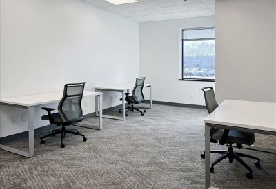 Bright workspace featuring three white desks and ergonomic mesh chairs.