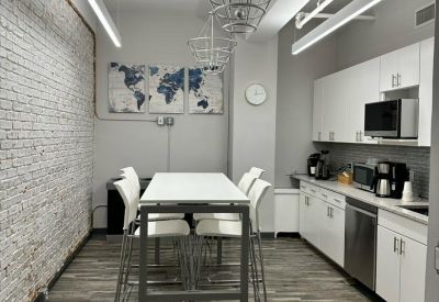 Communal kitchen and dining space with a white high-top table and exposed brick wall.