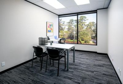 Private two-person office with grey carpet and a large window.