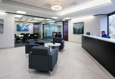 Spacious office lobby with contemporary armchairs, reception desk and art.