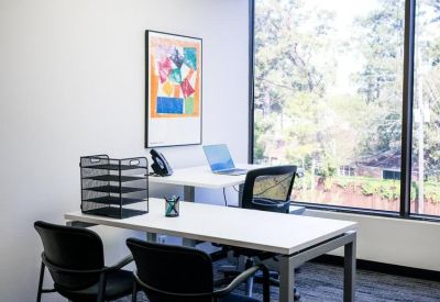 Individual workstation with a white desk, ergonomic chairs, and colorful abstract art.