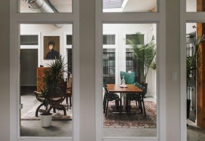 View through internal windows of a communal meeting space with a portrait on the wall.