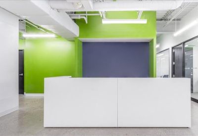 Modern reception desk with vibrant green and blue accent walls and industrial ceilings.