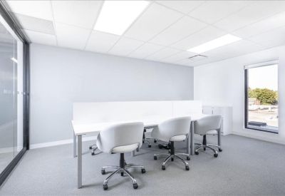Bright office space with a white desk partitioned for three workstations and ergonomic chairs.