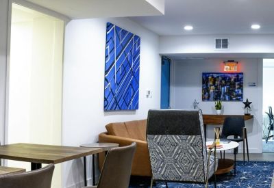 Modern lounge area with leather sofa, patterned armchair, and abstract blue wall art.