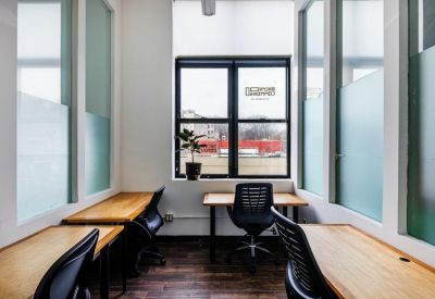Private office suite featuring three wooden desks and views of the neighborhood.