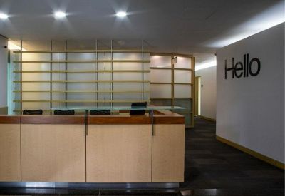 Professional reception area with a wood-paneled desk and a white wall featuring a Hello sign.