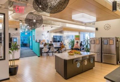 Modern communal kitchen with wood floors, island, and hanging orb light fixtures.
