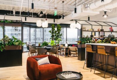 Spacious communal lounge area with velvet armchairs, potted plants, and floor-to-ceiling windows.