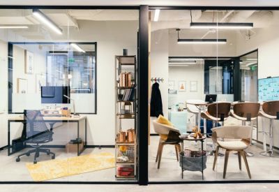 Modern glass-walled office suites featuring a workstation and a collaborative high-top table.