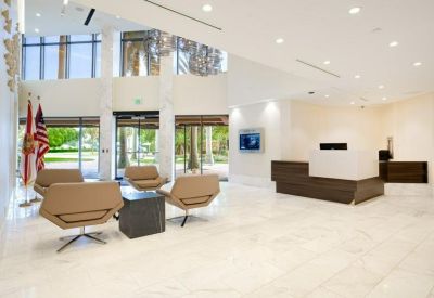Spacious white marble lobby with modern tan armchairs and a reception desk.
