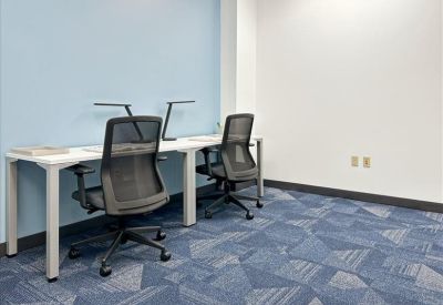 Private office suite with a white desk and large window overlooking trees.