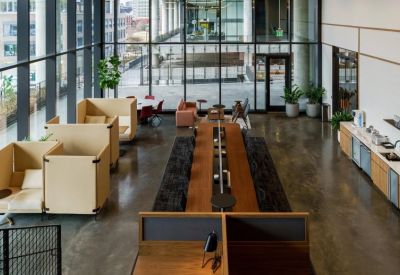 Spacious communal coworking area with high-back booths, a long wooden table, and floor-to-ceiling windows.