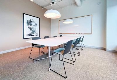 Bright conference room with a large white table and black wire chairs.