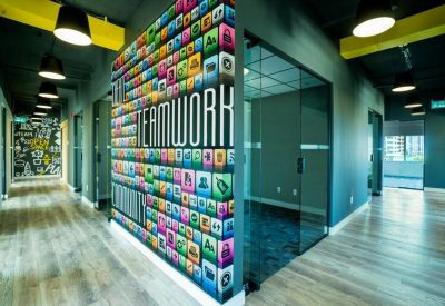 Stylish corridor with a colorful teamwork mural and glass-walled private offices.
