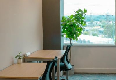 Bright workspace featuring two wooden desks and a large window overlooking the city.