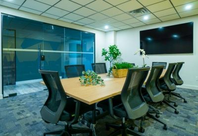 Modern boardroom with a light wood table, black mesh chairs, and a large wall-mounted screen.