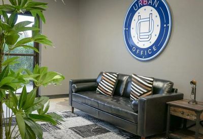 Bright waiting area with a leather sofa, patterned rug, and circular wall signage.