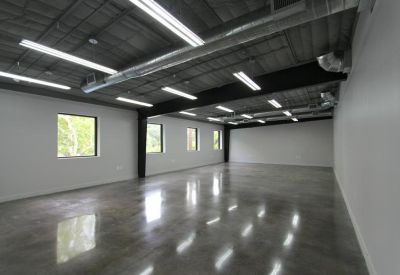 Empty open-plan office space with polished concrete floors and exposed industrial ceiling.