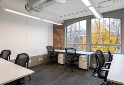 Bright office workspace with arched windows, white desks, and ergonomic black chairs.