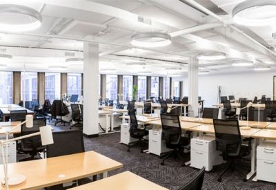 Large open-plan workspace with numerous rows of desks and ergonomic black chairs.