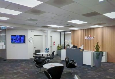 Modern reception area with grey desk, accent plant, and black designer chairs.