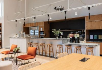 Modern communal kitchen and cafe area with a white marble bar and wooden stools.